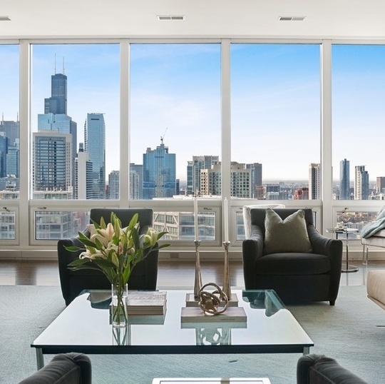 Furnished high-rise living room with floor-to-ceiling windows overlooking the Chicago skyline.